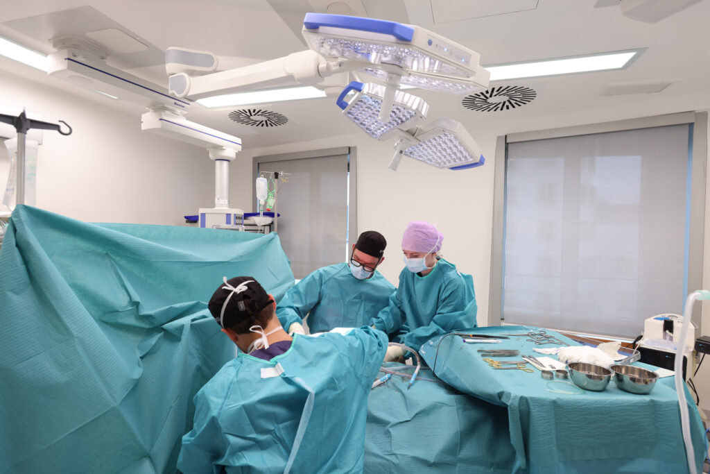 Einblick in den OP-Bereich bei Plastmed Düsseldorf mit mehreren Ärzten und Assistentinnen in Kitteln