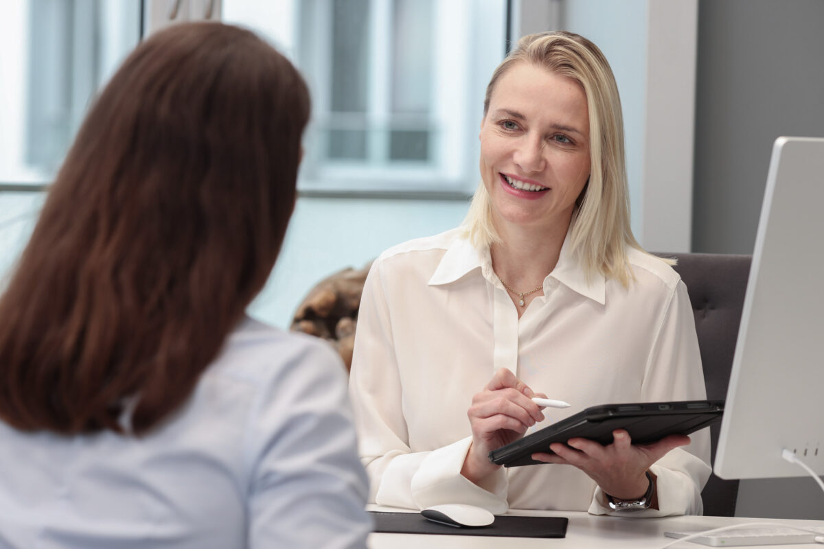 Frau ist beim Erstgespräch für eine intimchirurgische Bahandlung bei Plastmed Düsseldorf, durchgeführt von Dr. med. Naja-Norina Pluto, die ein Tablet in der Hand hält