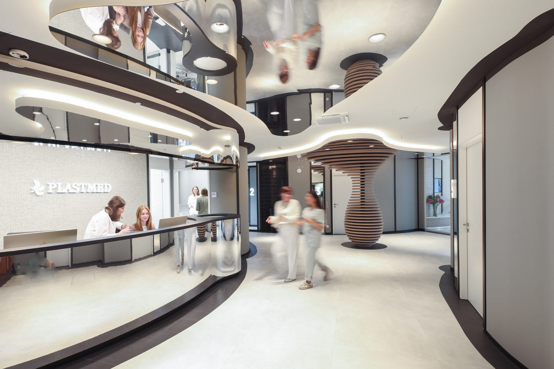 Empfang und Eingangsbereich mit Skulptur in der Plastmed Privatklinik in Düsseldorf, zwei Ärzte unterhalten sich und man sieht Mitarbeiter am Empfang