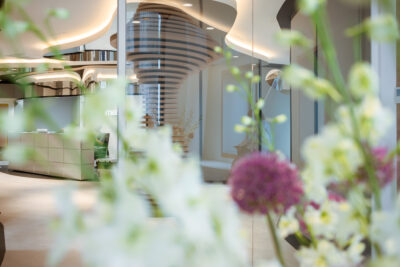 Empfang und Eingangsbereich mit Skulptur in der Plastmed Privatklinik in Düsseldorf, im Vordergrund Blumen verschwommen