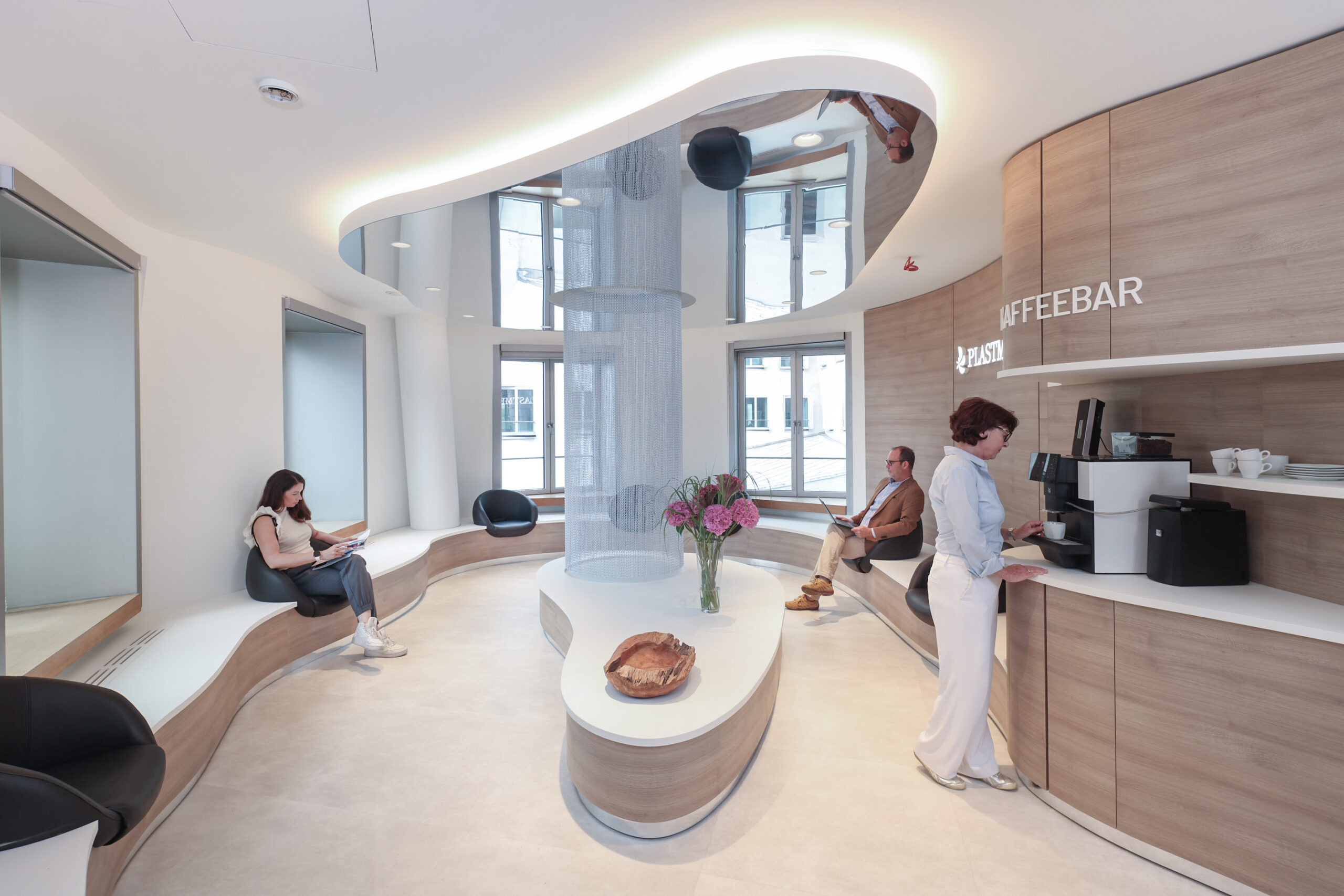Wartebereich mit Kaffeebar in der Plastmed Privatklinik in Düsseldorf, drei Patienten warten