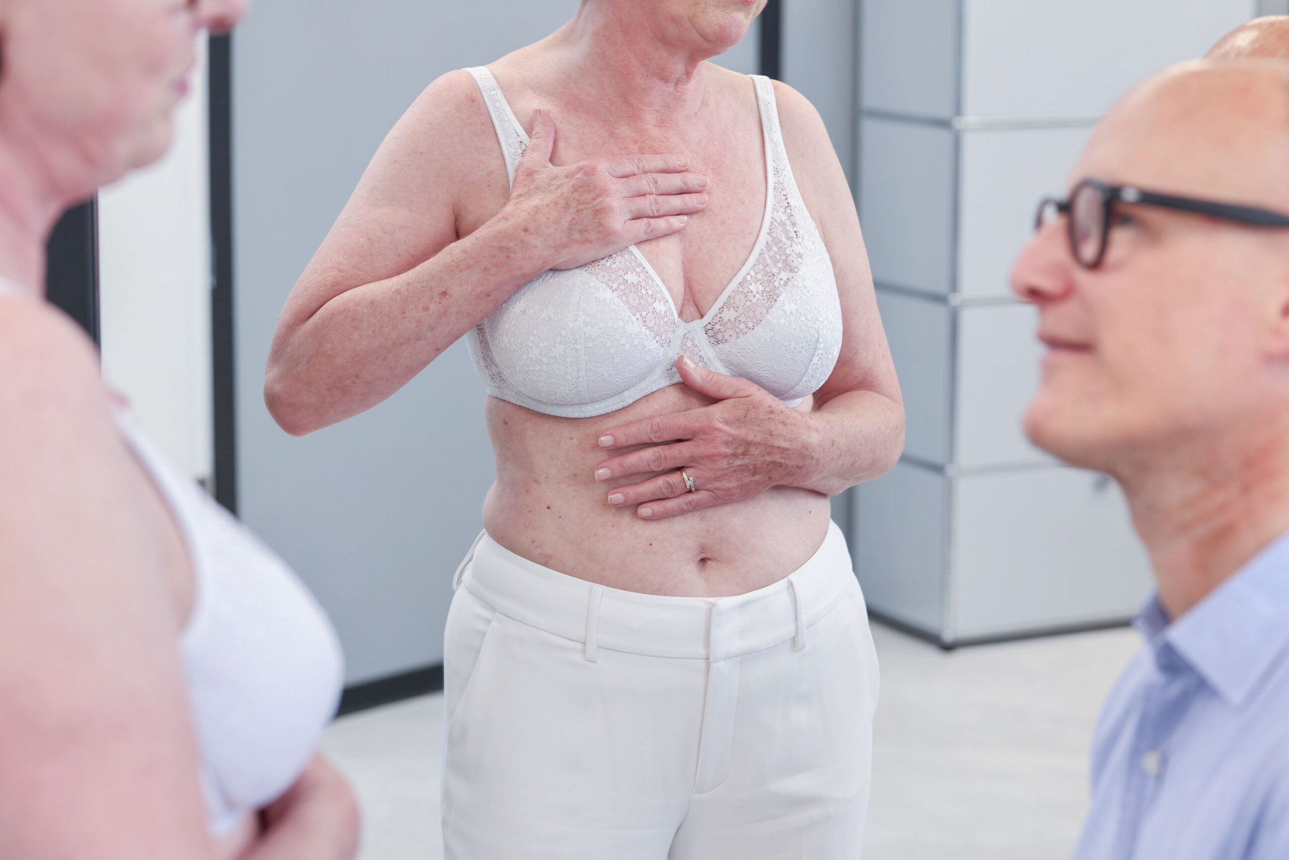 Frau wird vor einer Bruststraffung, Brustvergrößerung oder -verkleinerung bei Plastmed Düsseldorf untersucht von Dr. med. Till Scholz, der ihre Brust begutachtet.